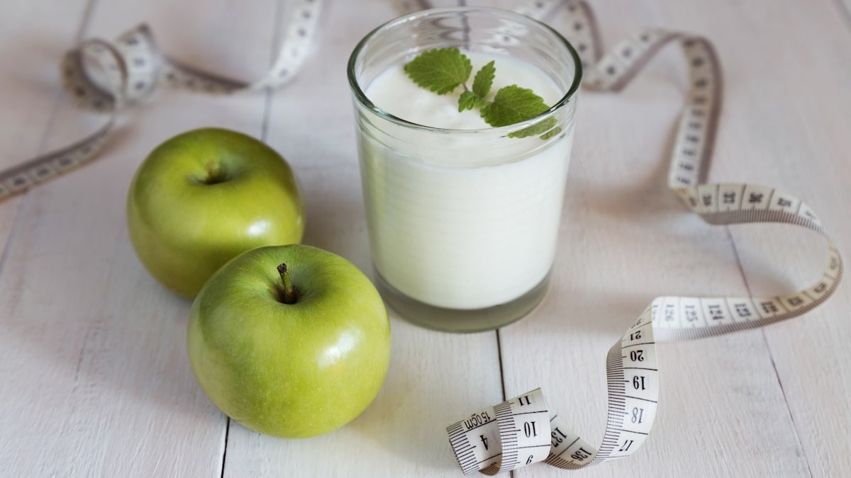 Green apples, glass of yoghurt and measure tape